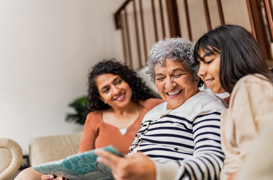 Grandmother, mother and child smiling and reading together